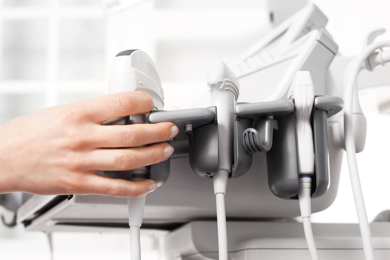 A doctor reaches for an ultrasound unit.