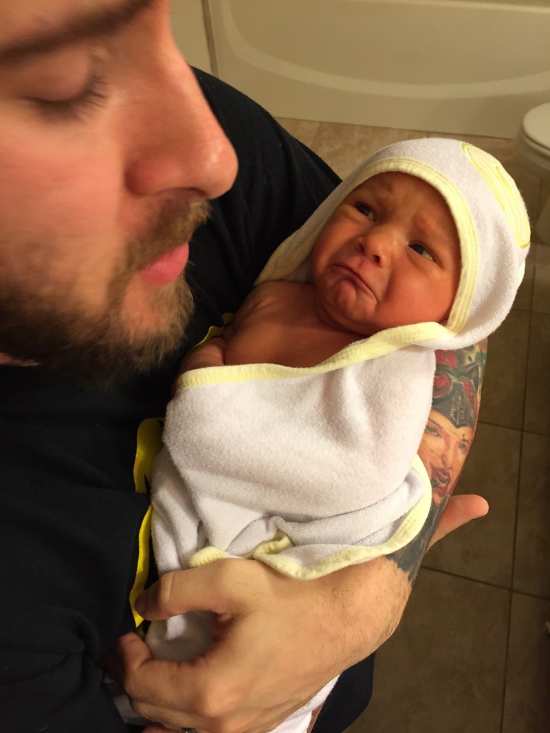 A father holds his newborn daughter after giving her a bath.