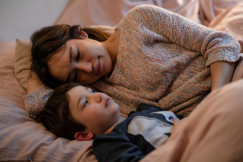 Mother shares her bed with her child.