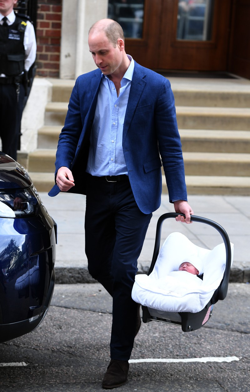 Prince William uses a baby seat in which Prince Louis is lying.