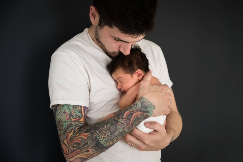 The father kisses his newborn girl on the head, thinking about a name for her.