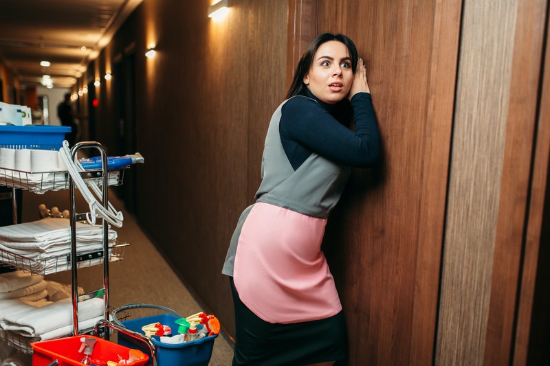 A hotel employee listens at the door of a room, because she suspects a bad move.