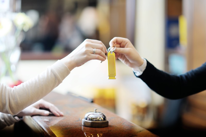 A photo of the reception of a hotel, where the hotel employee gives the key to a guest.