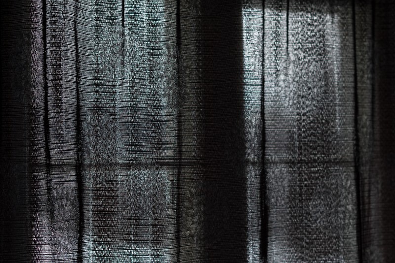 Gros plan d'un rideau noir et translucide fermé devant une fenêtre