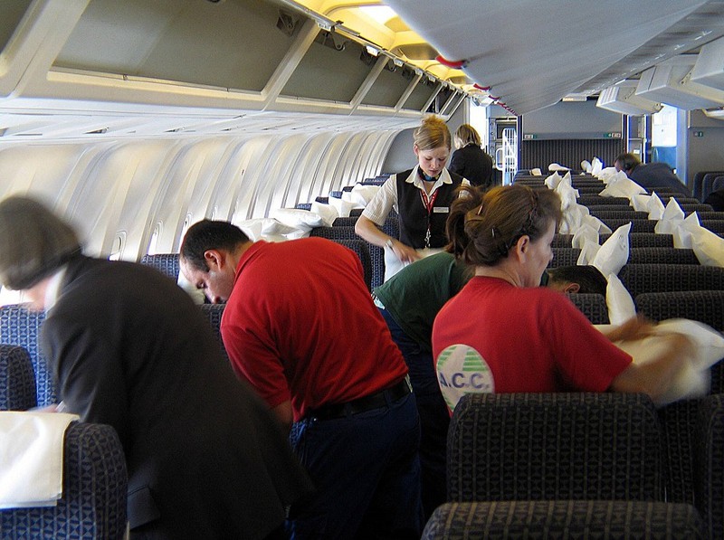 Several people are packing away their luggage on the plane and waiting for departure