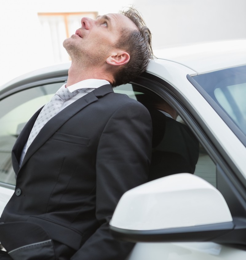 Upset businessman leaning on his car Upset