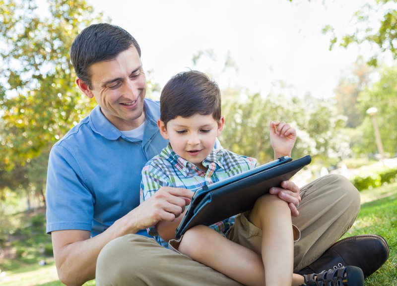 A father has fun with his son on a tablet